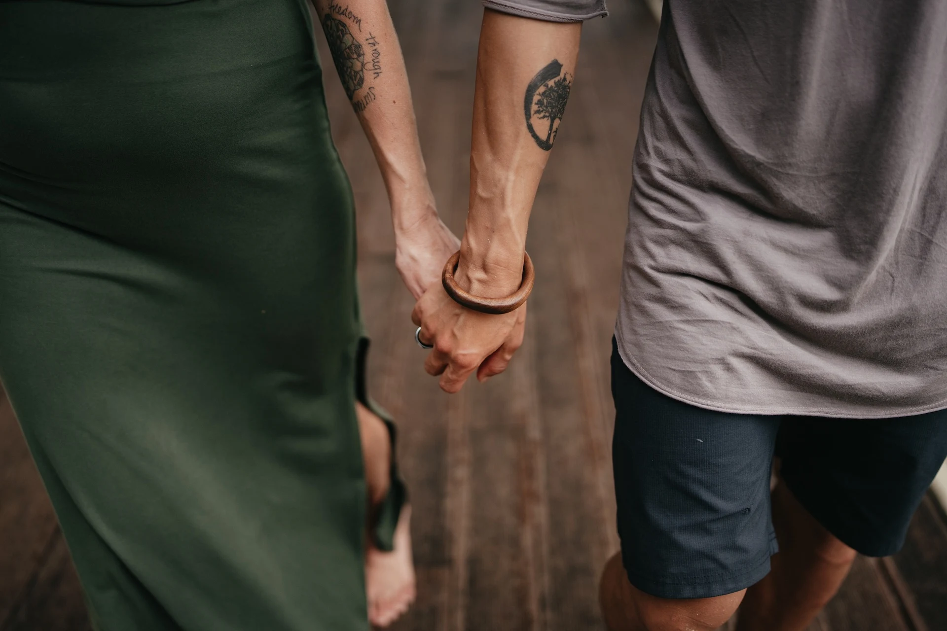 A couple walking hand in hand on a wooden path